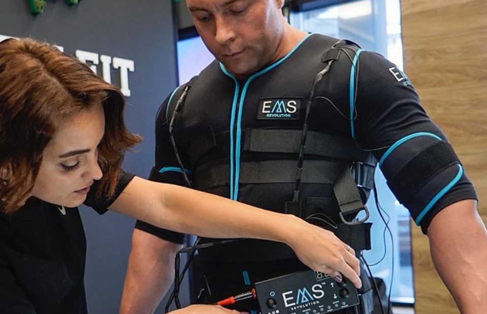 Trainer stelt EMS apparatuur in tijdens persoonlijke training